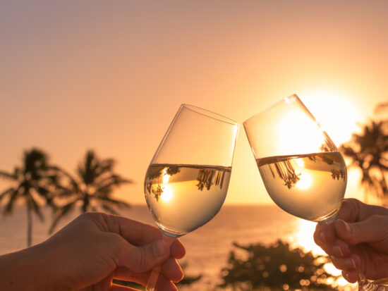 Wine glasses in a beautiful sunset beach setting.